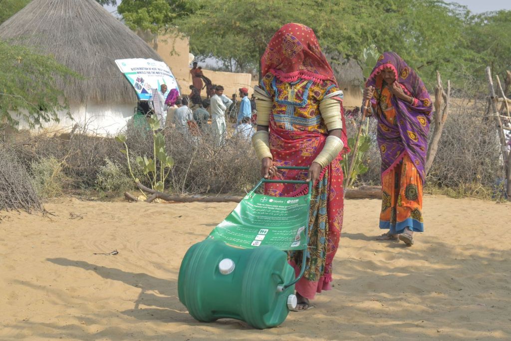 A woman carrying water by rolling the H2O (Help-2-Others) Wheel up the rough terrain to her home in Tharparkar. The ground bears the weight of the 40 litre Wheel, relieving her of the severe physical strain. Photo: Tayaba (Organisation)Tayaba beneficiaries on their way to collect water in Tharparkar desert.