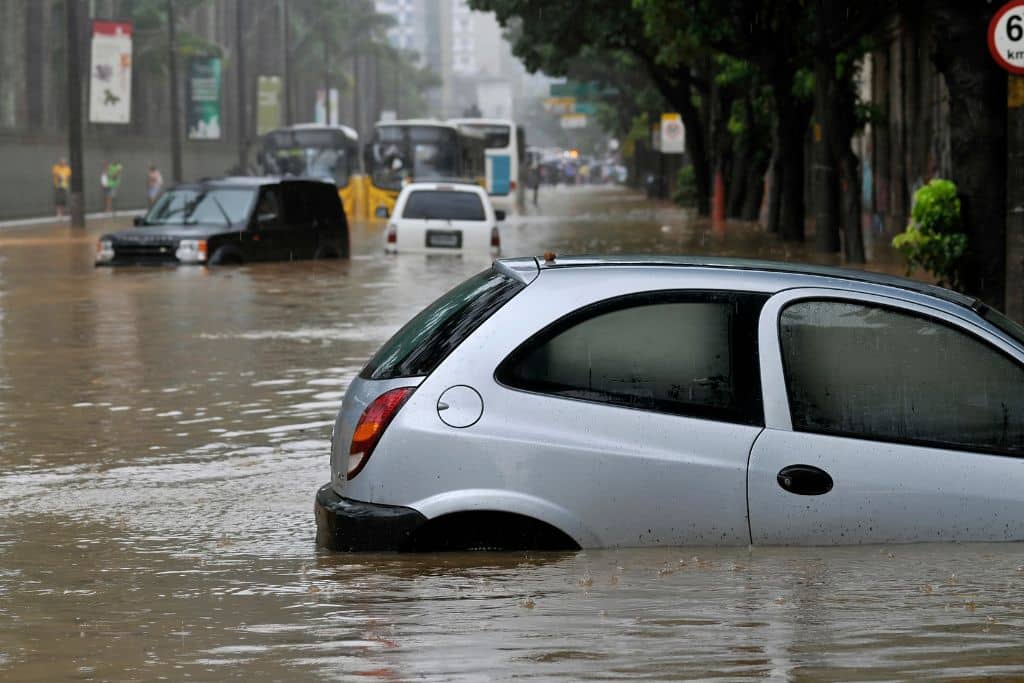 car on a flooded road being swept away by water