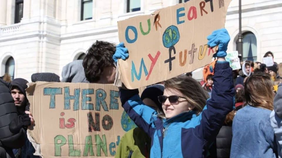 A young at a climate protest holding a sign reading "Our Earth my future".