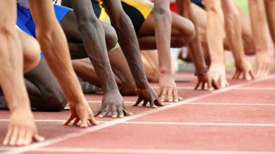 Athletes line up at the starting line on a running track.