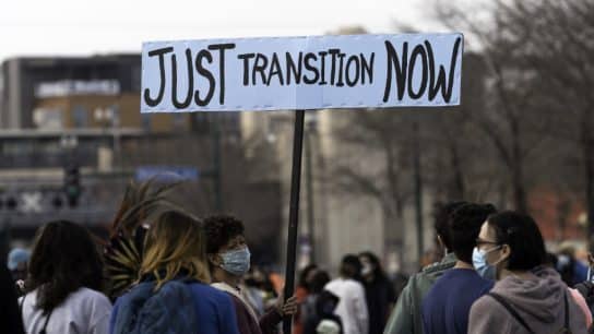 A woman holds a Just Transition Now sign at a rally in Minneapolis, Minnesota.