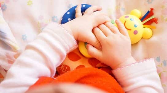 Toddler holding a yellow plastic toy.