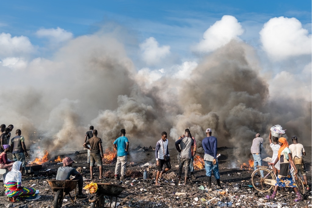 Young men and women are pictured burning electrical wires to recover copper at Agbogbloshie, Accra, Ghana on September 2, 2019.